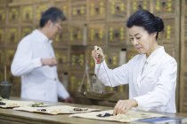 Reife Chinesin wägt Kräuter in Apotheke — Stockfoto