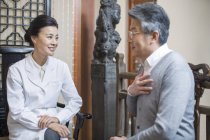 Doctora china hablando con paciente senior - foto de stock