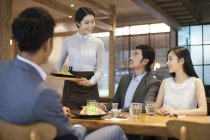 Chinese waitress serving people in restaurant — Stock Photo