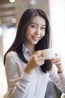 Chinês mulher segurando xícara de café no café — Fotografia de Stock