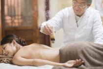 Senior Chinese doctor performing moxibustion therapy on woman — Stock Photo