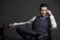 Confiante empresário chinês sentado no sofá, estúdio tiro — Fotografia de Stock