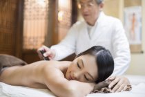 Médico chinês sênior realizando massagem de raspagem em paciente do sexo feminino — Fotografia de Stock