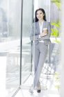 Chinese businesswoman holding cup of coffee at work — Stock Photo