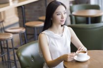 Chinês mulher sentada com xícara de café no café — Fotografia de Stock
