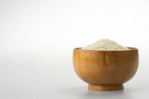 Сырой рис в деревянной чаше изолированы на белом фоне — стоковое фото