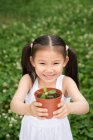 Menina chinesa jovem segurando uma planta em vaso no parque — Fotografia de Stock