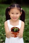 Junges chinesisches Mädchen hält eine Topfpflanze im Park — Stockfoto