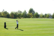 Jovem chinês tomando um balanço de golfe — Fotografia de Stock