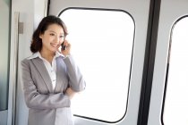 Young chinese businesswoman calling on phone by windows — Stock Photo