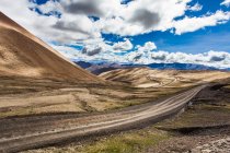 Strada con vista sulle montagne e cielo nuvoloso, Tibet, Cina — Foto stock