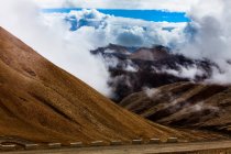 Route avec vue sur les montagnes et ciel nuageux, Tibet, Chine — Photo de stock