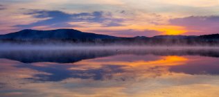 Lago com reflexão céu por do sol e montanhas — Fotografia de Stock