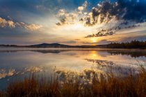 Lago con el reflejo del cielo puesta del sol y montañas - foto de stock