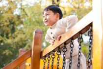Chino niño jugando en parque infantil juguete puente - foto de stock
