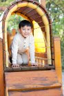 Rapaz chinês a rastejar através do túnel no parque infantil — Fotografia de Stock