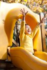 Esctatic ragazza cinese che gioca sul parco giochi scivolo — Foto stock