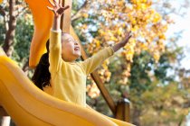 Menina chinesa jogando no playground slide — Fotografia de Stock