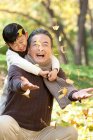 Китайский мальчик с дедушкой смотрит, как падают листья — стоковое фото