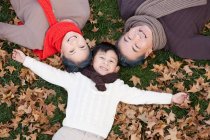 Chinesischer Junge mit Großeltern liegt im Herbst im Gras — Stockfoto
