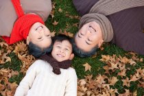 Chinese boy with grandparents lying on the grass in autumn — Stock Photo