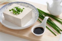Тофу в мисці з соєвим соусом і зеленою цибулею — стокове фото