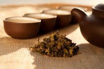 Trockene Teeblätter, Kannen und Tassen im Sonnenlicht — Stockfoto