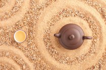Tee in Kannen und Tassen auf Sandoberfläche, Ansicht von oben — Stockfoto