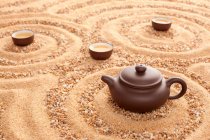 Tea set in pot and cups on sand surface — Stock Photo