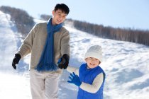 Китайский отец играет с сыном в снегу — стоковое фото