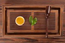 Chá na xícara, folhas verdes e colher de madeira — Fotografia de Stock