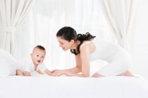 Happy Chinese mother and baby boy in bedroom — Stock Photo