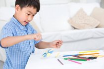 Китайський хлопчик виготовляє паперові іграшки. — стокове фото