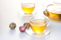 Set de té de vidrio con olla y té en tazas aisladas sobre fondo blanco - foto de stock