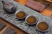 Китайский чайник и чашки чая подряд — стоковое фото