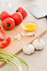 Ingredienti per la cottura su tavola di legno, aglio, uovo in ciotola e pomodori — Foto stock