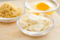 Uova, zenzero tritato e fette di aglio in ciotole di vetro — Foto stock