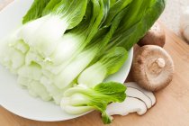Bok choy and mushrooms on wooden surface — Stock Photo