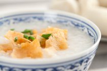 Chinesisches Essen, Reisbrei in Schüssel mit Chips und grünen Zwiebeln — Stockfoto
