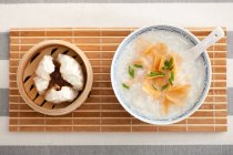 Schüssel mit Reisbrei und gedämpften Brötchen auf dem Tisch serviert — Stockfoto