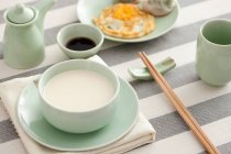Latte di soia con cibo e bacchette serviti in tavola — Foto stock