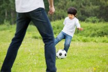 Щасливий китайський батько з сином грають у футбол. — стокове фото