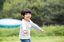 Glücklicher chinesischer Junge spielt Frisbee — Stockfoto