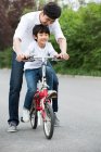 Père chinois enseignant fils à faire du vélo — Photo de stock