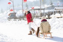 Enfants chinois heureux jouant avec traîneau dans la neige — Photo de stock