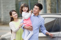 Feliz joven familia china y coche - foto de stock