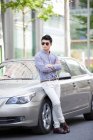 Giovane uomo cinese appoggiato alla sua auto — Foto stock