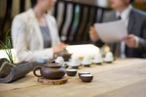 Set da tè tradizionale cinese in ceramica con pentola e tazze, persone sfocate sullo sfondo — Foto stock