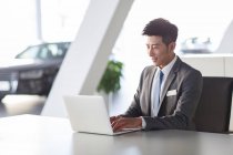 Young chinese businessman working with laptop in office — Stock Photo