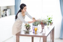 Young Chinese woman arranging flowers at home — Stock Photo